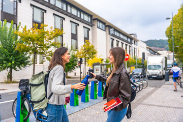 Fototapeta premium Young student friends sharing a flask and talking outdoors