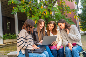 Group of young women collaborating on laptop for university project
