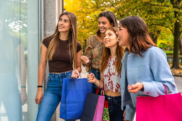 Women friends enjoying autumn window shopping with bags