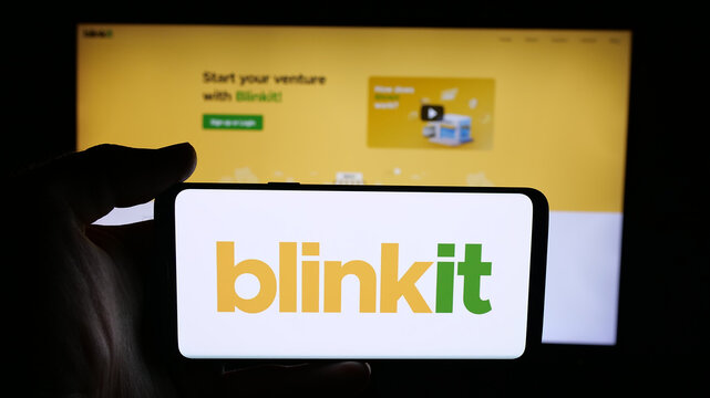 Stuttgart, Germany - 11-02-2025: Person holding cellphone with logo of Indian company Blinkit (Blink Commerce) on screen in front of webpage. Focus on phone display.