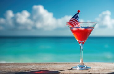 Patriotic cocktail in martini glass. US flag party hat on top. Red white and blue cocktail at beach. Independence Day July 4th celebration drink with ocean background.