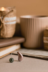 Modern hearing aid lying on soft surface near cozy decor. Audiology