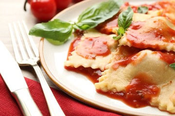Delicious ravioli with tomato sauce and basil served on light wooden table, closeup