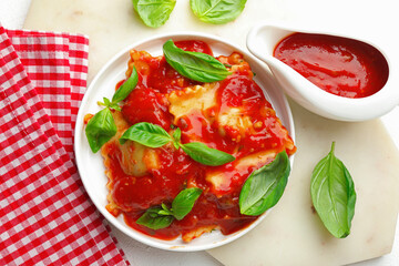 Delicious ravioli with tomato sauce and basil on white table, flat lay