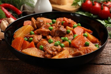 Delicious cooked stew and fresh ingredients on wooden table, closeup