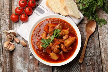 Delicious cooked stew in bowl served on wooden table, flat lay