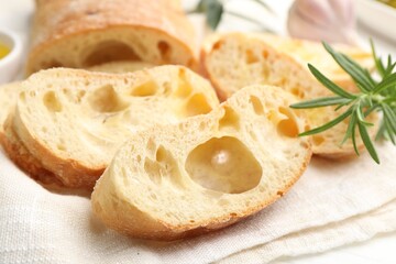 Fresh cut ciabatta and rosemary on white table, closeup