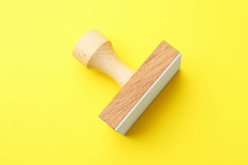 One wooden stamp on yellow background, top view