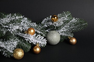 Beautiful Christmas tree branches with ornaments on black background, closeup