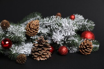 Beautiful Christmas tree branches with cones and ornaments on black background, closeup