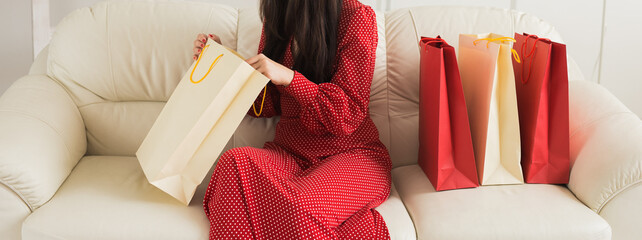 Unpacking new clothes from colorful shopping bags. Banner with copy space. Concept of shopping excitement and personal style