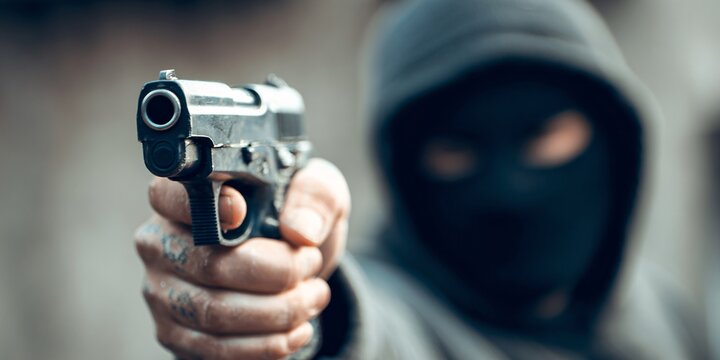 Person in a hoodie pointing a gun towards the viewer