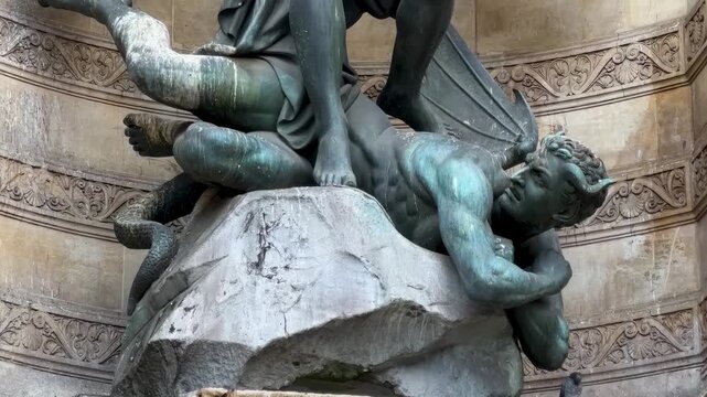 Ultra close-up of Saint Michael bronze sculpture with sword, wings, and demon.