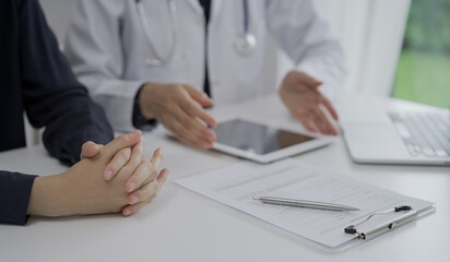 Doctor and a patient in clinic. The female physician is using tablet computer for filling up medication history record form, close up of woman hands. Medicine and science
