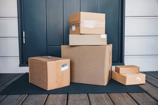 An Array of Brown Cardboard Boxes Stacked Neatly on a Doorstep, Showcasing Various Sizes and Packaging Materials in a Home Delivery Context