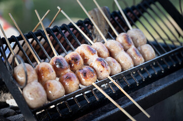Grilled sausage bamboo skewer street food thailand charcoal grill smoky vendor snack market outdoor