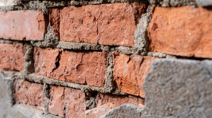 An old brick wall with ruins.The cement masonry is falling off the wall.Substandard construction.