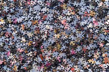 A photo of the background from a colored puzzle.There are a lot of puzzle pieces on the table.Logical tasks for the mind.