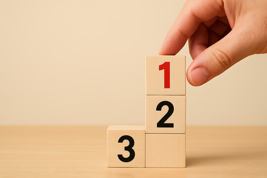 Hand stacking wooden blocks with numbers one two and three indicating steps priority ranking growth development and successful business process planning