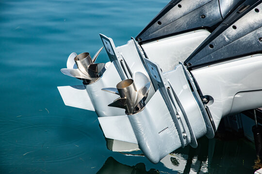 Close-up detail of outboard motor and propeller on docked marine boat, elevated above the water