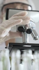 Close up of white gloved hand of a scientist adjusting a microscope in a laboratory. Medicine, health care and science concept