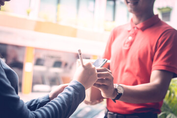 A person wearing red T-shirt is delivering parcels to a satisfied client. Friendly worker