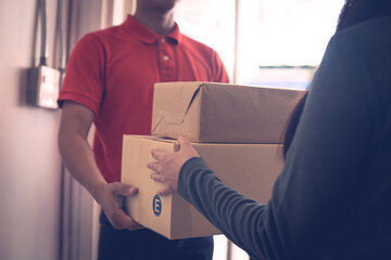 A person wearing red T-shirt is delivering parcels to a satisfied client. Friendly worker