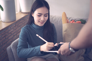 Courier Delivering Package To Woman, Client Signing on tablet