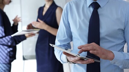 Businessman hands holding and using a digital tablet for work, navigating information and checking data during a modern corporate meeting - Powered by Adobe