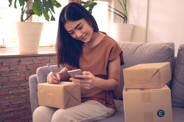 Woman writing address for delivery, filling information on parcel box
