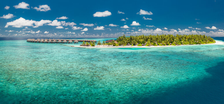Breathtaking Maldives tropical island panorama: luxury resort water villas on a vast turquoise ocean lagoon with clear sunny blue sky. Idyllic summer vacation travel destination backdrop for tourism