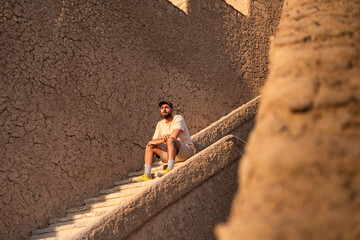 Young man relaxing on ancient mudbrick stairs in sunset oman