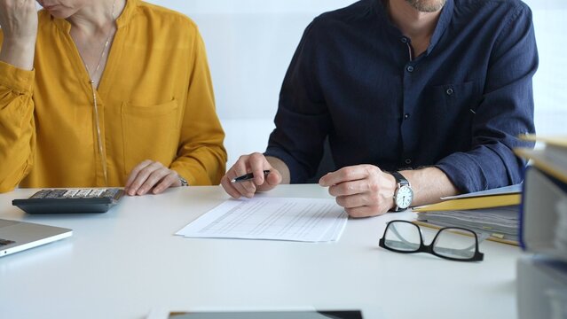 Professional team analyzing contract details, reviewing financial documents, calculating costs at collaborative workplace with laptops and paperwork. Audit and taxes in business - Powered by Adobe