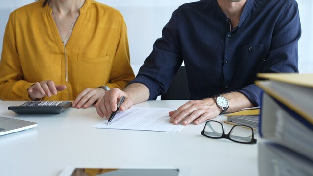 Professional team analyzing contract details, reviewing financial documents, calculating costs at collaborative workplace with laptops and paperwork. Audit and taxes in business