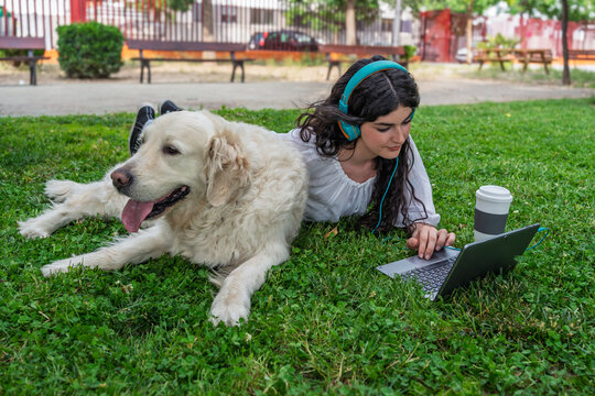 Freelancer working with her dog in a park using laptop - Powered by Adobe