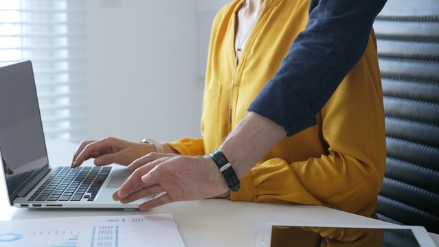 Business colleagues are collaborating on a project, analyzing financial charts and using a laptop to input data in a modern office setting. Businesspeople concept
