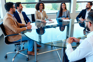 Group of young adult multiethnic men and women sitting around glass table discussing business strategy during meeting in modern office, smiling and engaging with each other