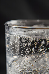 Close-Up of Effervescent Qinine-Infused Tonic Water n Clear Glass Illuminated gainst Neutral Background