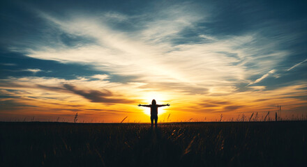 Obraz premium Silhouette of a person with arms outstretched embracing the vibrant sunset sky with dramatic clouds and warm golden light