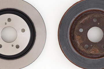 New and old rusty brake discs on light gray table background. Car spare parts. Compare two objects....