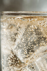 Close-Up of Effervescent Qinine-Infused Tonic Water n Clear Glass Illuminated gainst Neutral Background