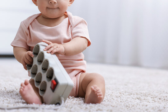 Cute little baby with power strip on floor at home, closeup. Space for text