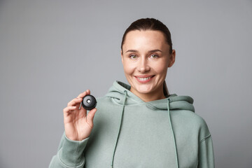 Fototapeta premium Young woman with hidden spy camera on light grey background