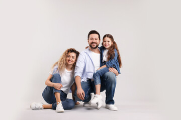 Obraz premium Happy parents and their daughter hugging on grey background. Family bonding