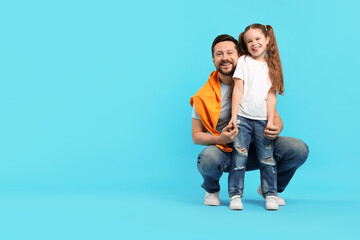 Happy father and his daughter posing on light blue background, space for text. Family bonding