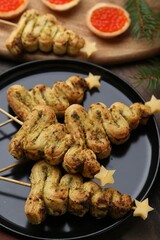 Christmas tree shaped snacks made with puff pastry, pesto sauce, cheese and festive decor on wooden table, closeup