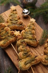 Christmas trees made with puff pastry, pesto sauce, cheese and festive decor on wooden table, closeup