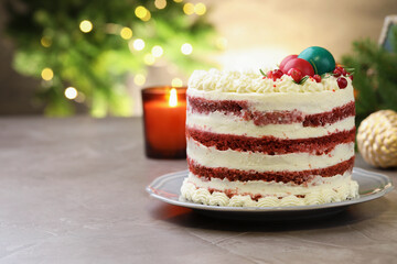 Delicious sponge cake with Christmas decor and red currants on grey textured table against blurred lights, closeup with space for text. Bokeh effect