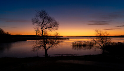 A baeutiful, colorful early spring sunrise over the lake with tree silhouettes. Seasonal landscape of Latvia, Europe.