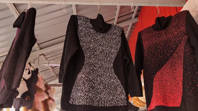 Colorful sweaters hanging in a fashion market showcasing unique designs and vibrant patterns at sunset